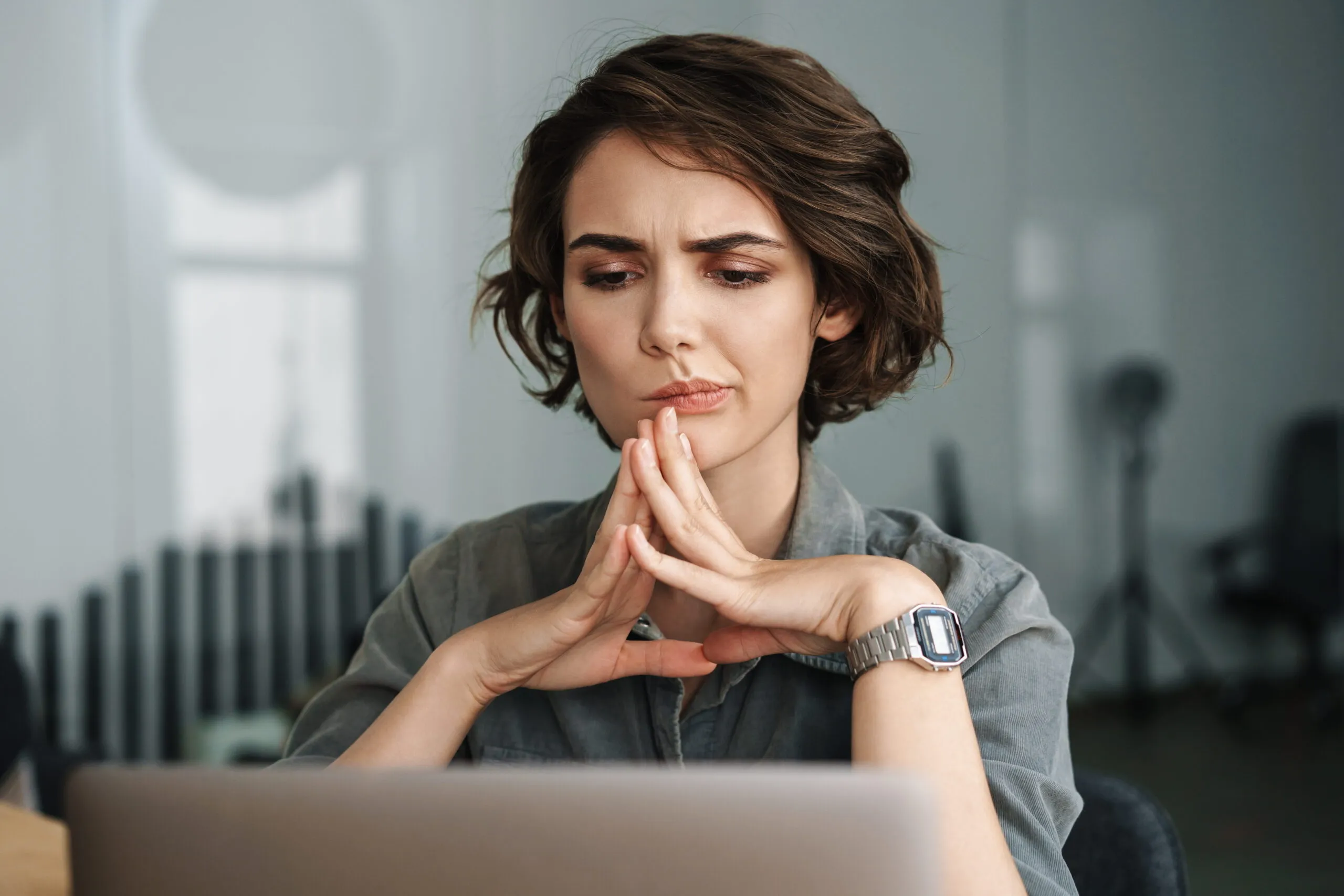 Woman holds hands under her chin looking at laptop while worried about IT support companies in Essex