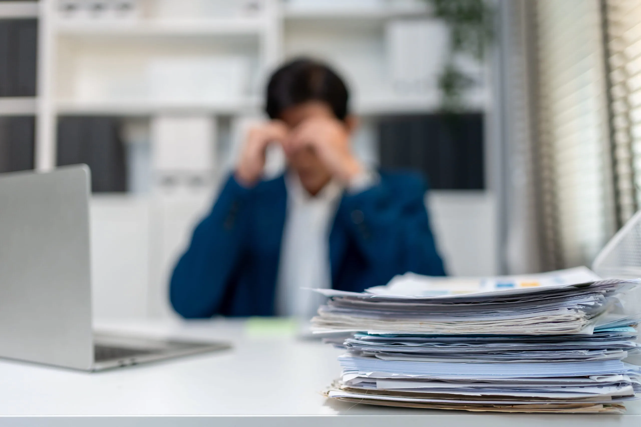 Blurry shot of a frustrated businessman working on table in office before discovering a IT consultancy in Essex that could help him with compliance.
