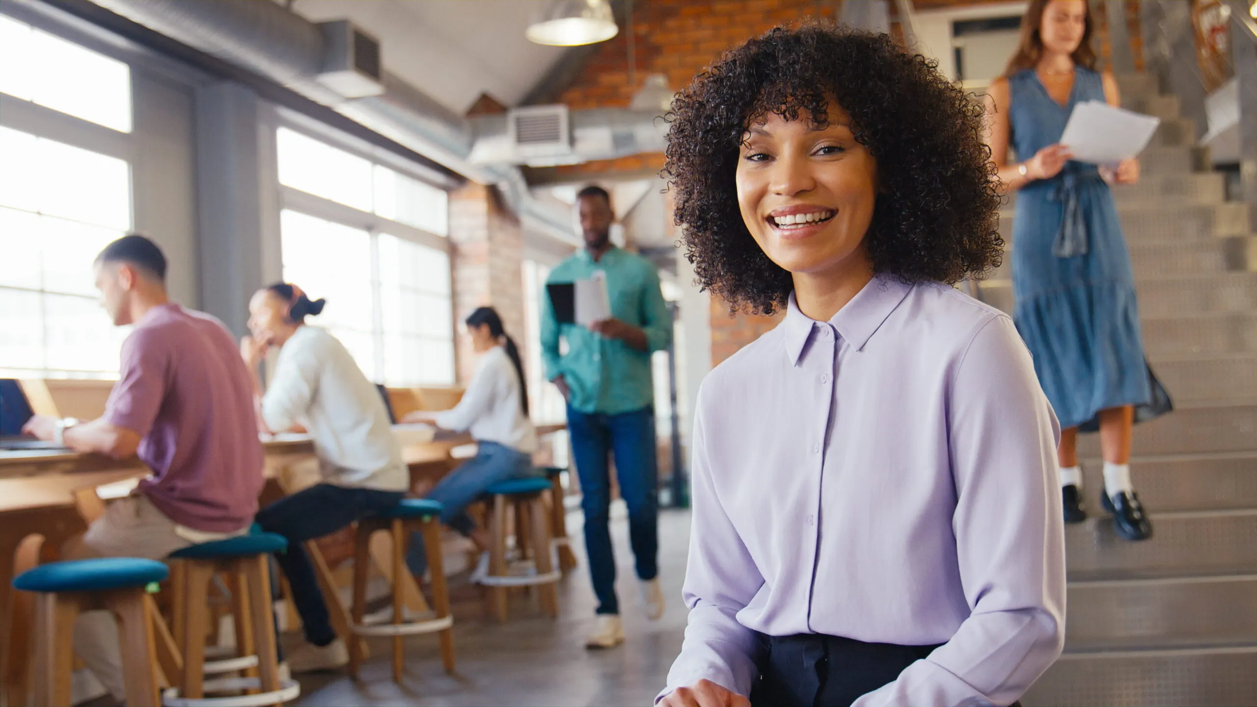 Smiling Businesswoman Working In Busy Open Plan Office after discovering outsourced IT support in Essex